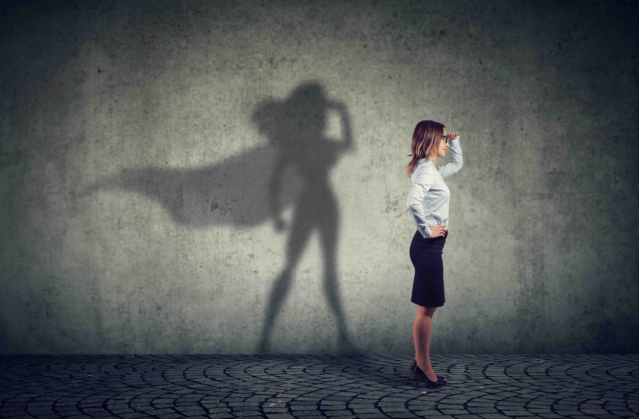 woman looking back with her shadow on the wall showing a superhero cape